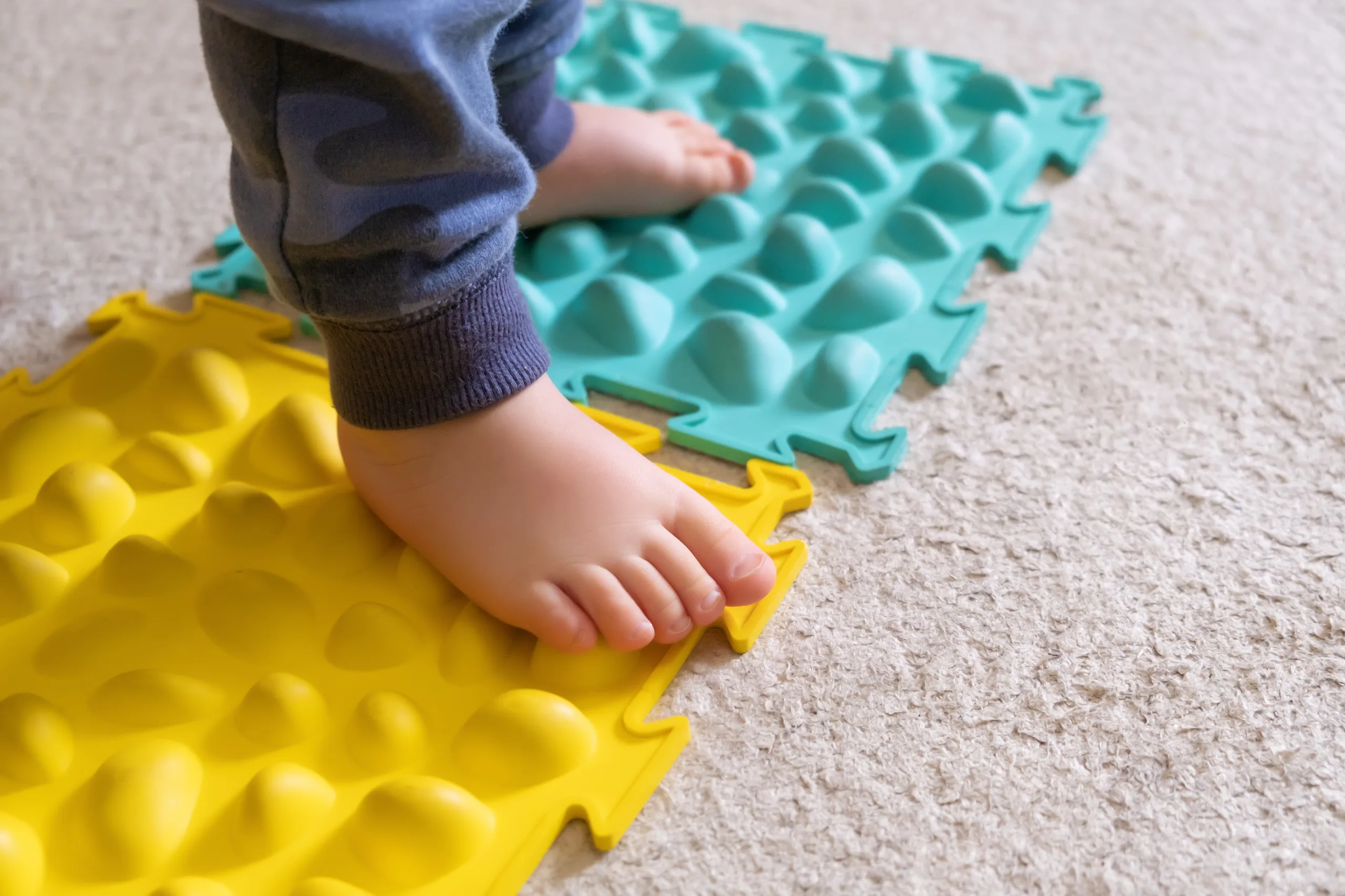 O REFÚGIO DO LAR: COMO AJUDAR CRIANÇAS ATÍPICAS NA REGULAÇÃO SENSORIAL. 1 pes pequenos de bebe no tapete com nervuras scaled