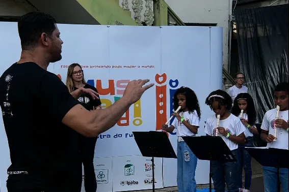 PROJETO MUSICARICANDO ORQUESTRA DO FUTURO APRESENTA RECITAL EM IPABA 2 Maestro Everson Salazar conduzindo os alunos durante o recital
